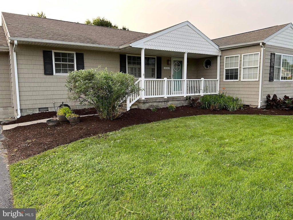 ranch-style house featuring covered porch and a lawn