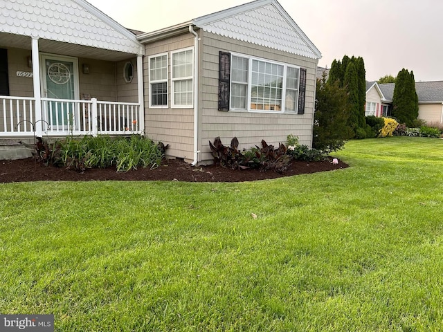 view of side of property featuring covered porch and a lawn