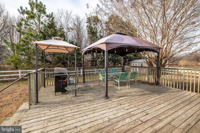 wooden terrace featuring a gazebo, grilling area, and a storage shed