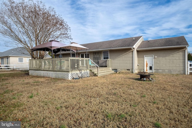 back of house featuring a gazebo, a deck, and a lawn