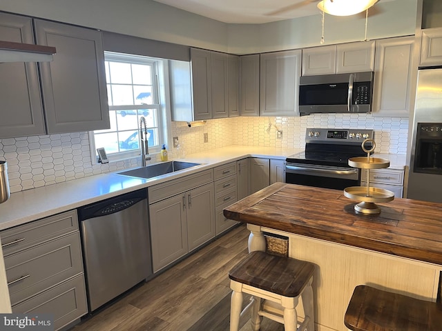 kitchen featuring sink, dark wood-type flooring, gray cabinetry, stainless steel appliances, and decorative backsplash