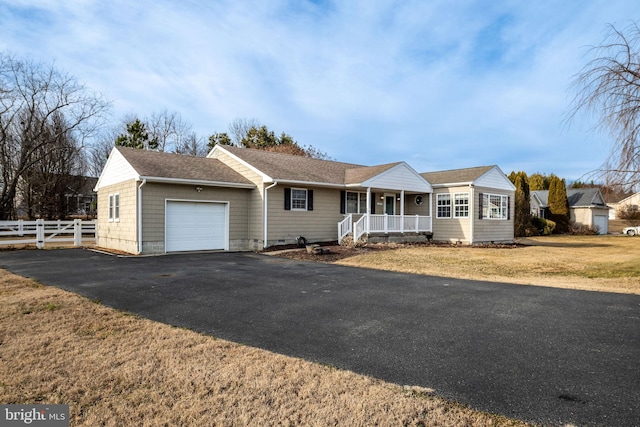 ranch-style house featuring a garage, a front yard, and covered porch