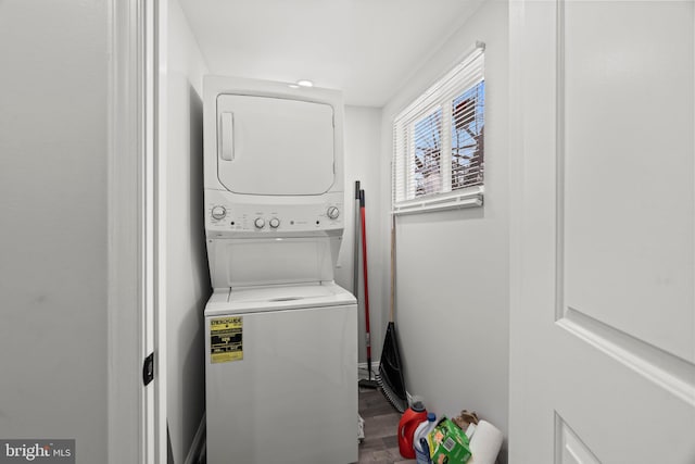 clothes washing area with hardwood / wood-style flooring and stacked washer / drying machine