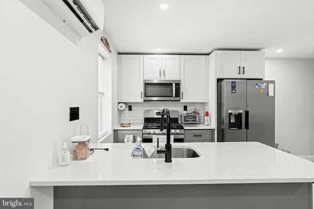 kitchen with sink, stainless steel appliances, white cabinets, decorative backsplash, and kitchen peninsula