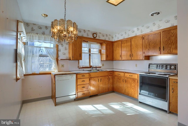 kitchen with sink, range, decorative light fixtures, white dishwasher, and a wealth of natural light