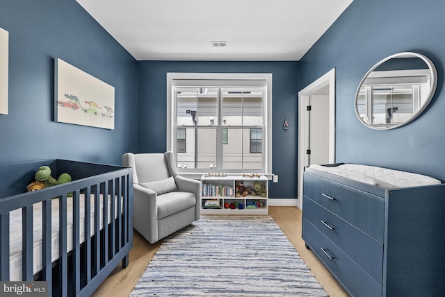 bedroom featuring a crib and light wood-type flooring