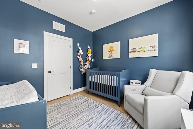 bedroom featuring a nursery area and hardwood / wood-style flooring