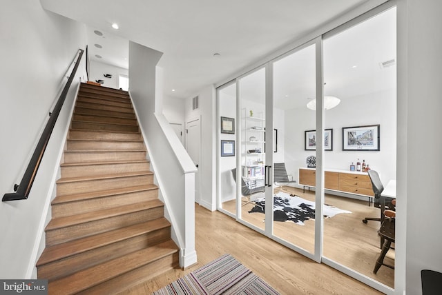 stairs featuring hardwood / wood-style flooring and a wall of windows