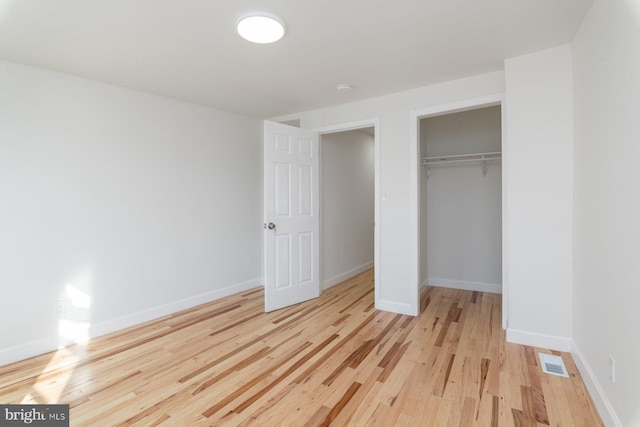 unfurnished bedroom featuring light wood-style flooring, baseboards, visible vents, and a closet