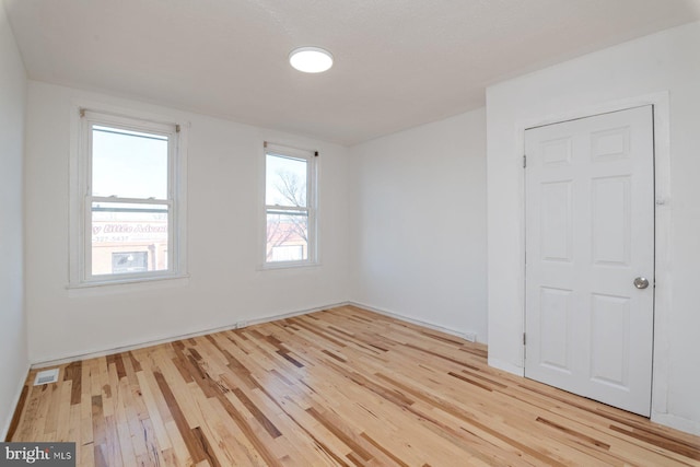 spare room featuring visible vents and hardwood / wood-style floors