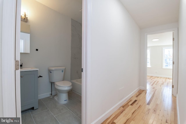 full bathroom featuring toilet, vanity, baseboards, and wood finished floors