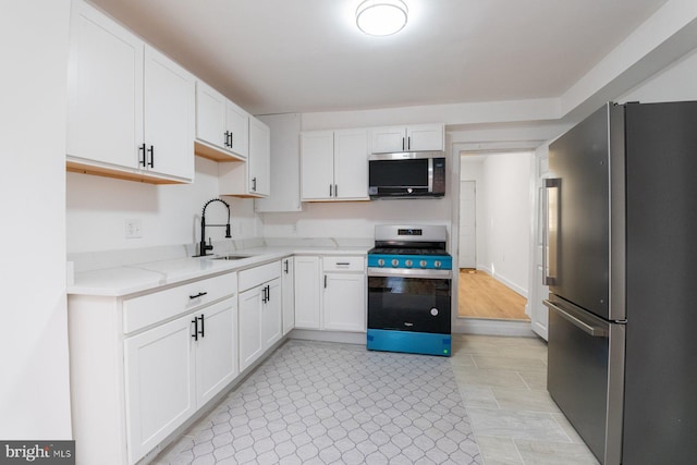 kitchen with a sink, stainless steel appliances, light stone counters, and white cabinets