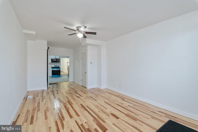 spare room with ceiling fan, baseboards, and light wood-style flooring