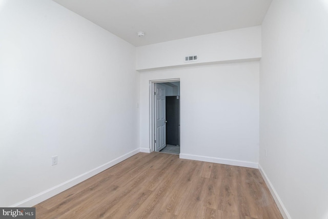 spare room featuring visible vents, light wood-type flooring, and baseboards