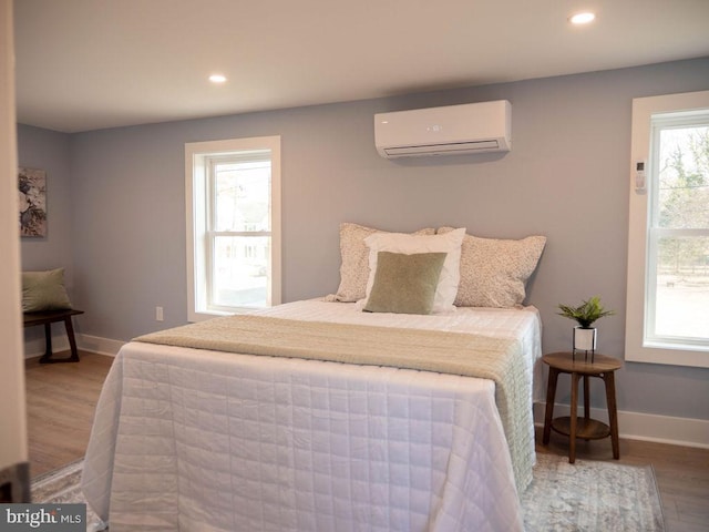 bedroom featuring a wall mounted AC and hardwood / wood-style floors