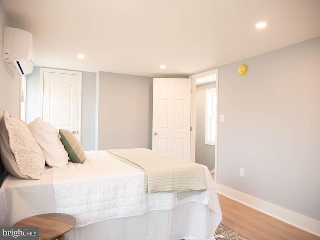 bedroom featuring a wall mounted AC and light wood-type flooring