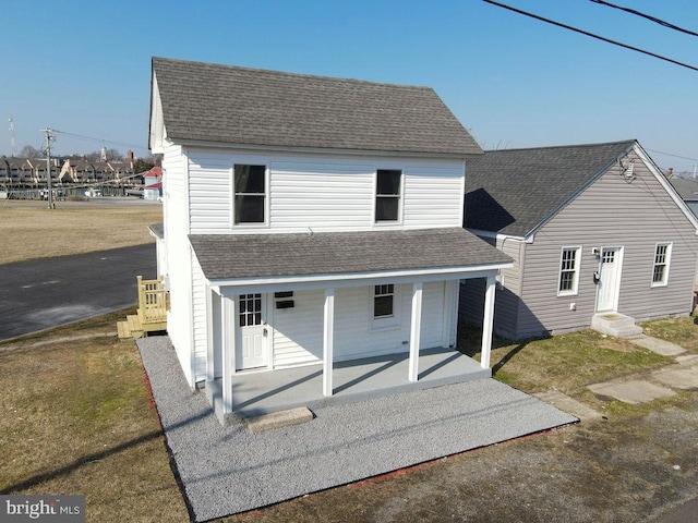 back of house featuring covered porch and a lawn