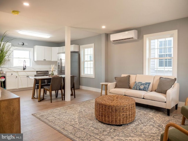 living room featuring sink, a wall unit AC, and light wood-type flooring