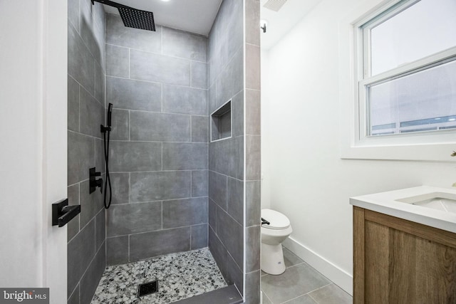 bathroom featuring tile patterned floors, toilet, vanity, and a tile shower