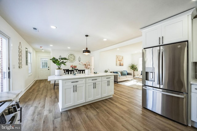 kitchen with white cabinetry, hanging light fixtures, light hardwood / wood-style flooring, and appliances with stainless steel finishes