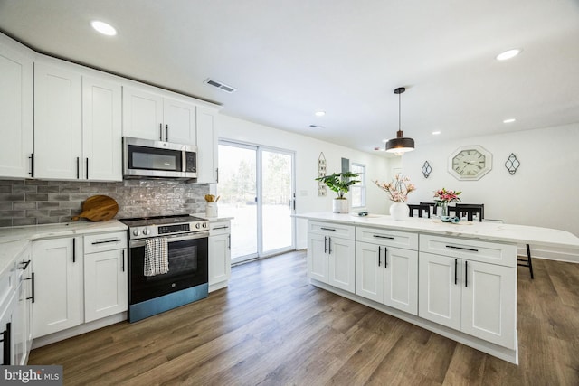 kitchen with stainless steel appliances, white cabinetry, hanging light fixtures, and backsplash