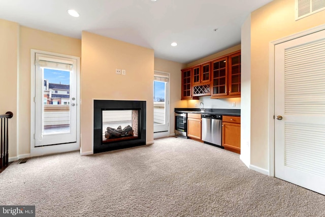 kitchen featuring dishwasher, sink, light colored carpet, and a multi sided fireplace