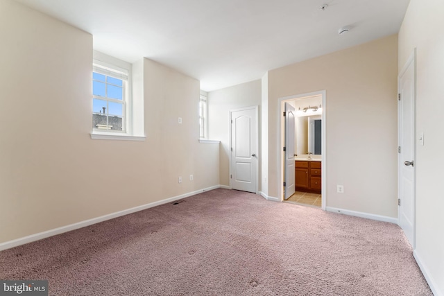 unfurnished bedroom featuring ensuite bathroom and light colored carpet