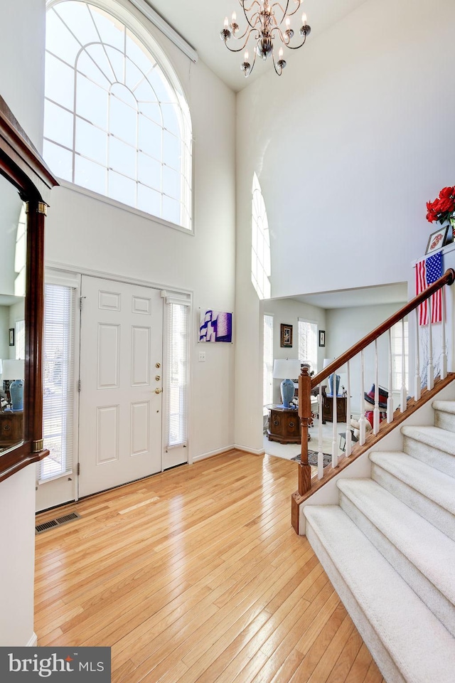 entrance foyer with a high ceiling, a chandelier, and light hardwood / wood-style floors