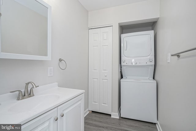 laundry area with stacked washer / dryer, sink, and dark wood-type flooring