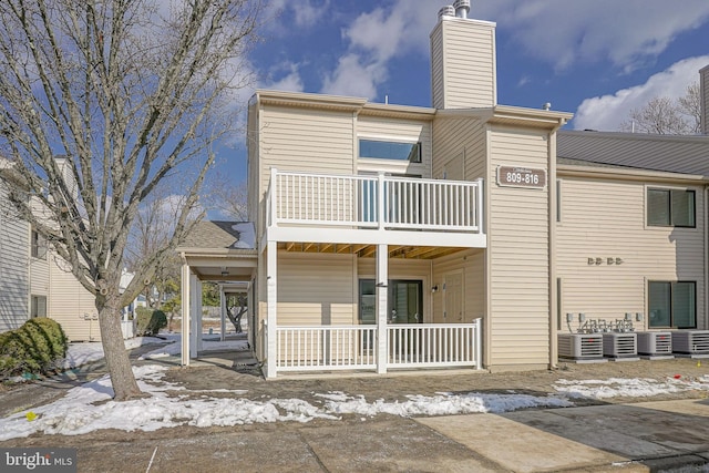 rear view of house featuring central AC unit and a balcony