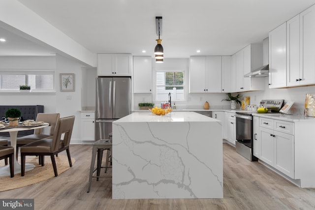 kitchen with stainless steel appliances, a center island, hanging light fixtures, and white cabinets