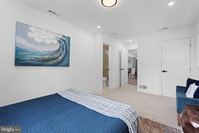 bedroom featuring ensuite bathroom and light colored carpet