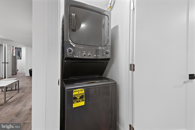 laundry area with stacked washer / drying machine and light hardwood / wood-style flooring