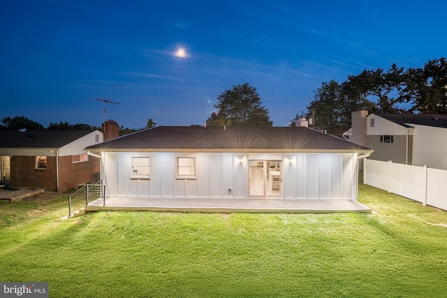 back house at dusk with a lawn