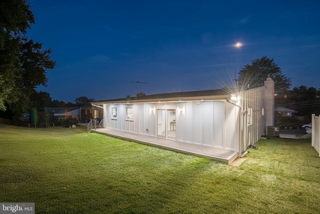 back house at night with a yard and central air condition unit