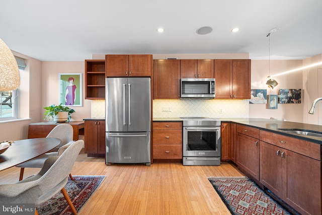 kitchen with sink, decorative light fixtures, light wood-type flooring, stainless steel appliances, and decorative backsplash