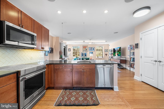 kitchen featuring sink, light hardwood / wood-style flooring, stainless steel appliances, tasteful backsplash, and kitchen peninsula