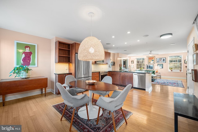 dining room featuring ceiling fan, sink, and light wood-type flooring