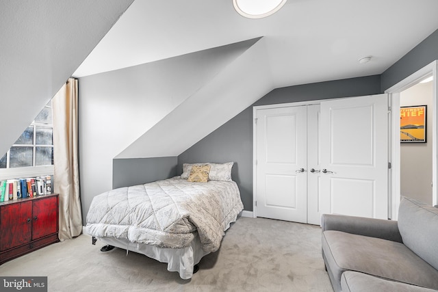 bedroom featuring vaulted ceiling, light colored carpet, and a closet