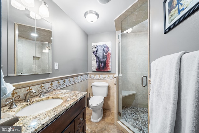 bathroom featuring toilet, tile walls, vanity, and a shower with shower door