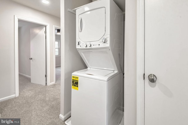 washroom featuring stacked washer / drying machine and light carpet