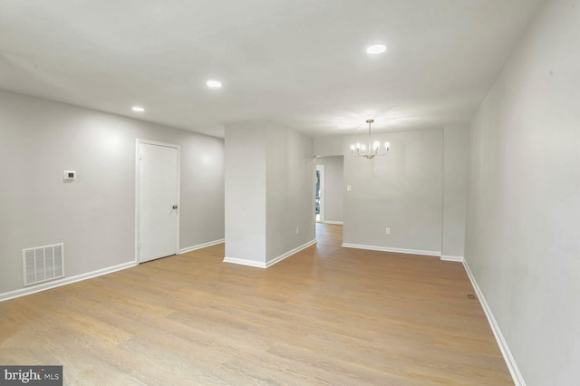 empty room with light hardwood / wood-style flooring and a notable chandelier