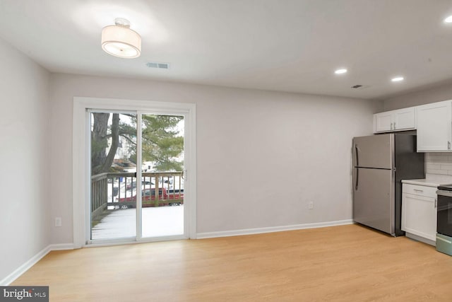 kitchen featuring tasteful backsplash, white cabinetry, appliances with stainless steel finishes, and light hardwood / wood-style floors