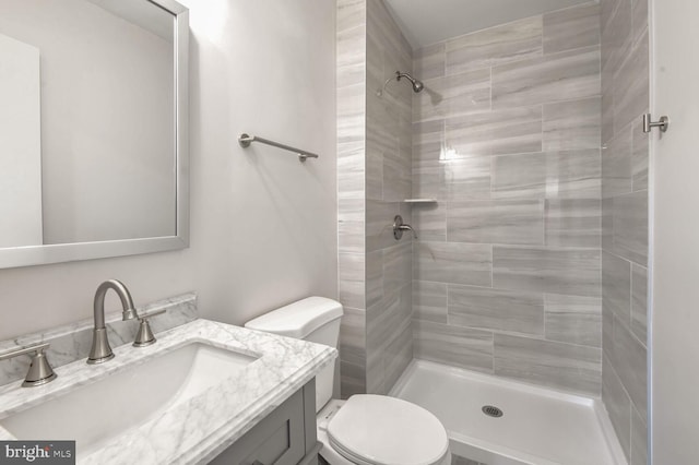 bathroom featuring vanity, toilet, and tiled shower