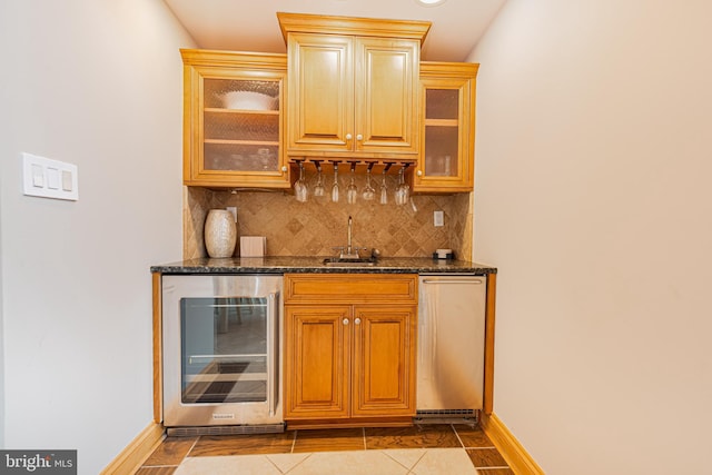 bar with sink, dark stone countertops, beverage cooler, decorative backsplash, and light tile patterned floors