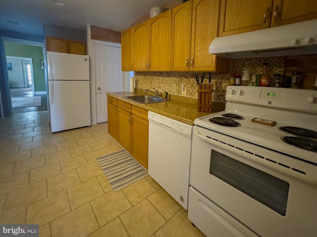 kitchen with white appliances, tasteful backsplash, light tile patterned floors, under cabinet range hood, and a sink