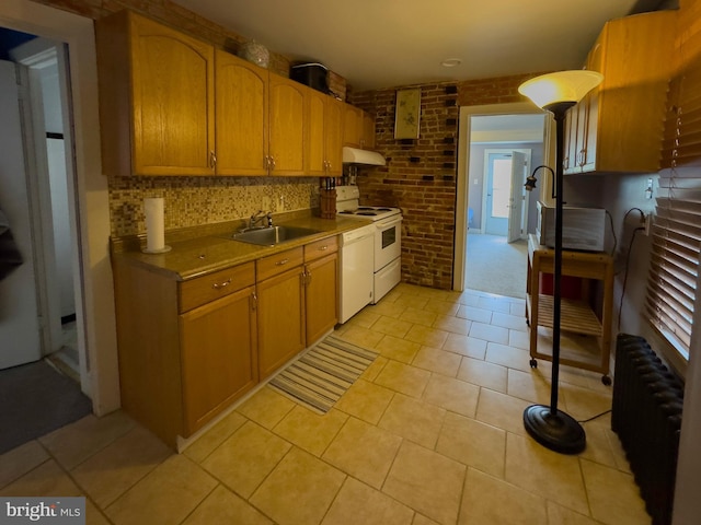 kitchen with under cabinet range hood, brick wall, a sink, radiator, and white range with electric cooktop