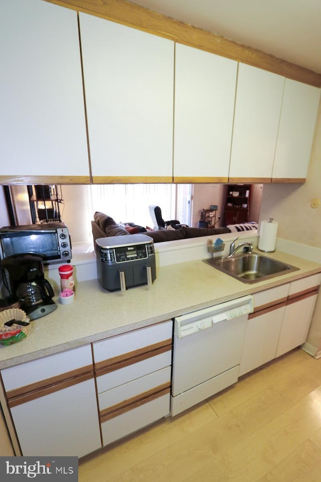 kitchen featuring light wood-type flooring, white dishwasher, sink, and white cabinets