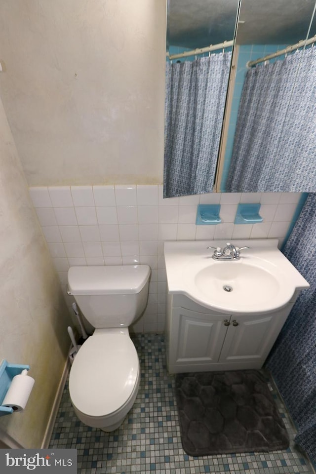 bathroom featuring sink, tile patterned flooring, tile walls, toilet, and walk in shower