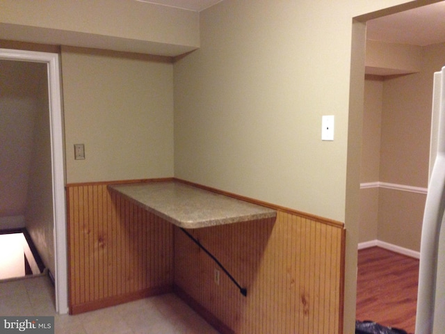 interior space featuring built in desk, wooden walls, and white fridge